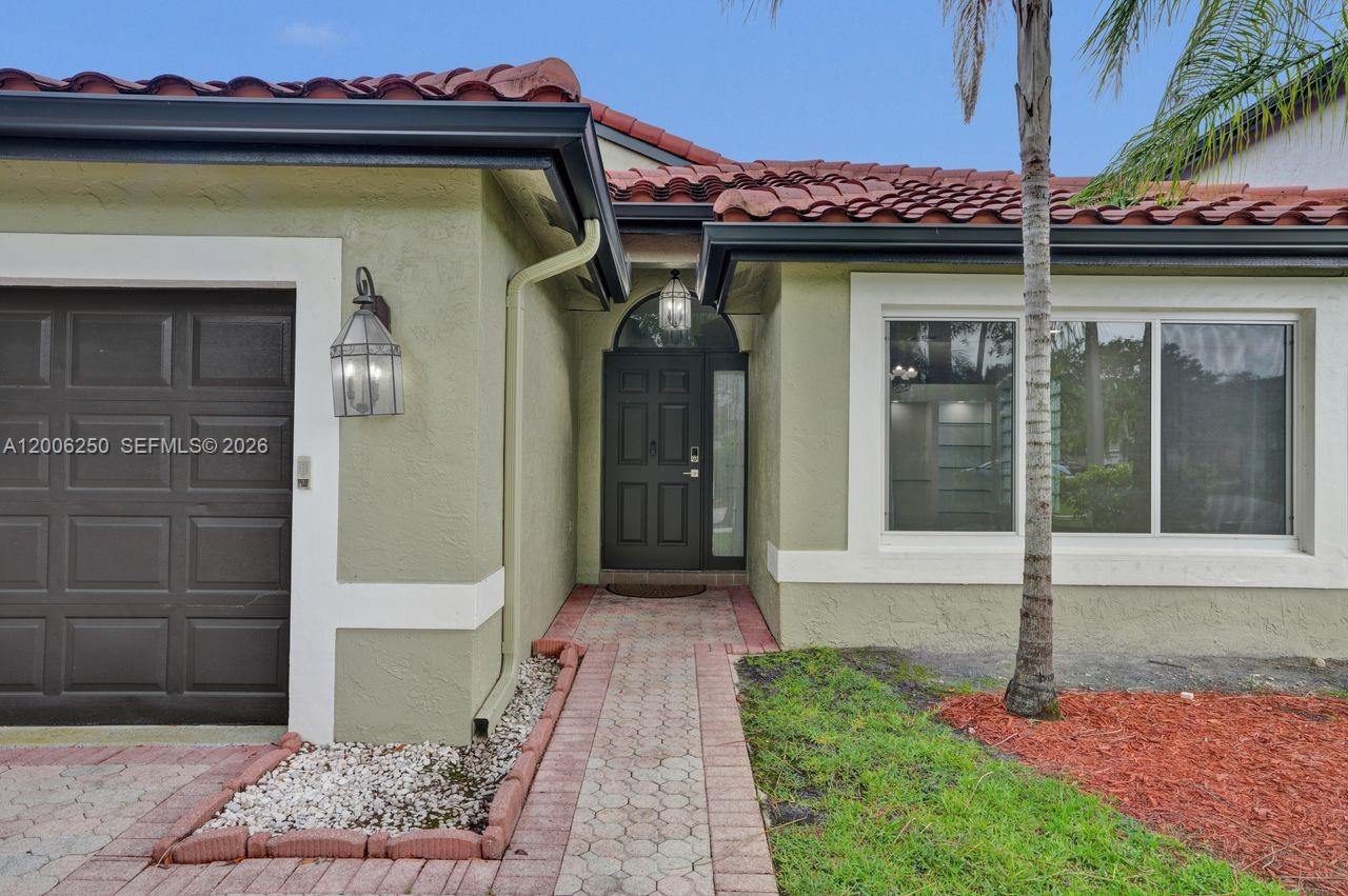 A modern kitchen with dark wood cabinets, stainless steel appliances, and tile flooring overlooks a patio — 17961 SW 27th St, Miramar FL 33029, MIRAMAR, FL