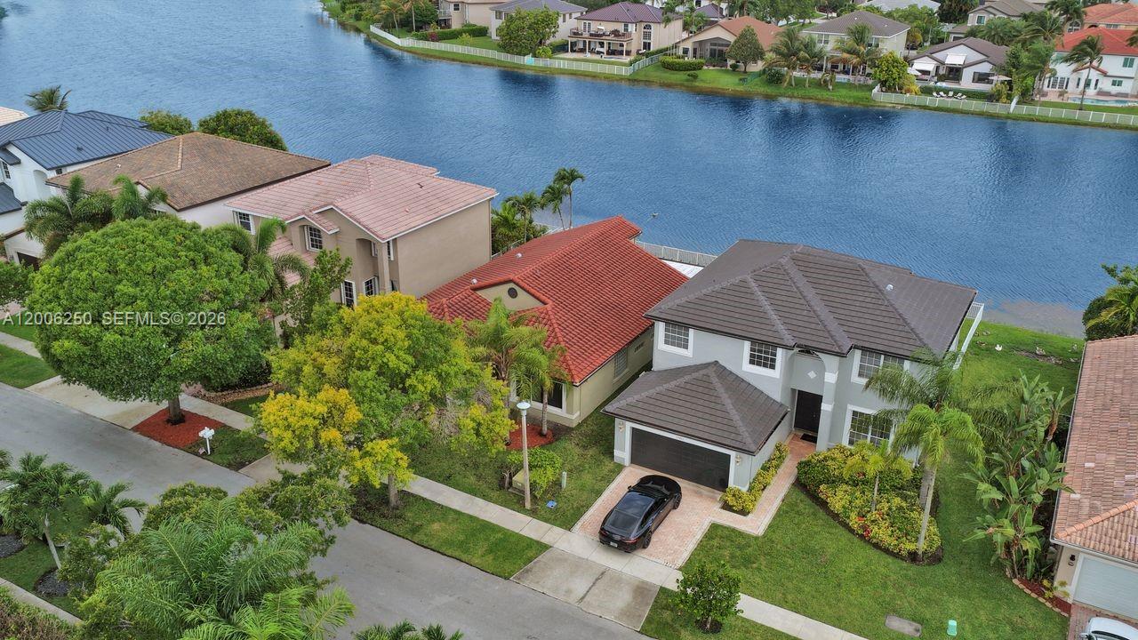 A bright, empty room features gray tile flooring, a chandelier, and a glass block window — 17961 SW 27th St, Miramar FL 33029, MIRAMAR, FL