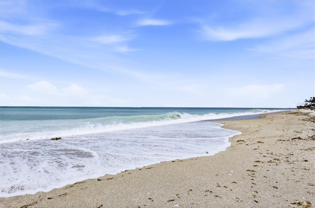 A sandy beach meets the ocean under a bright blue sky with light clouds — 1210 SHORE VIEW DRIVE UNIT B, ENGLEWOOD, FL
