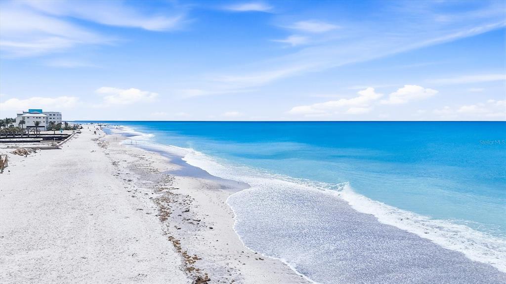 An aerial view shows a white sand beach meeting the turquoise ocean under a blue sky — 1210 SHORE VIEW DRIVE UNIT B, ENGLEWOOD, FL