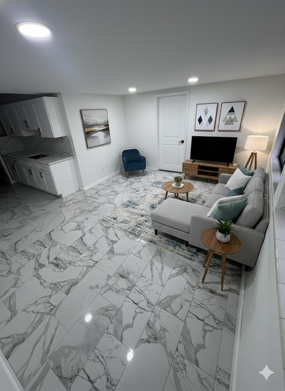 A living room with marble-look tile flooring, a gray sectional sofa, and an adjacent kitchenette — 7714 W POWHATAN, TAMPA, FL