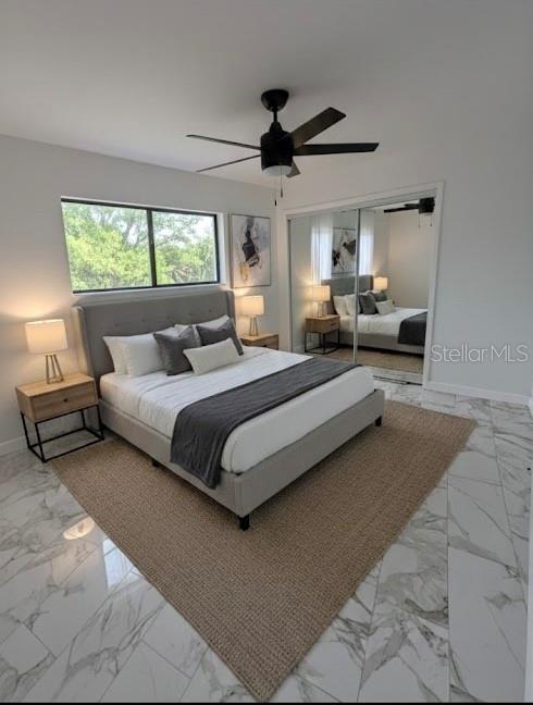 A modern bedroom features a gray upholstered bed, marble tile floors, and a ceiling fan — 7714 W POWHATAN, TAMPA, FL