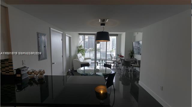 A modern apartment living and dining area features a black kitchen island and floor-to-ceiling windows — 92 SW 3rd St # 1802, Miami FL 33130, MIAMI, FL