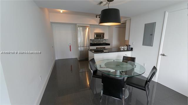 A dining area with a glass table and black chairs sits before a modern kitchen — 92 SW 3rd St # 1802, Miami FL 33130, MIAMI, FL