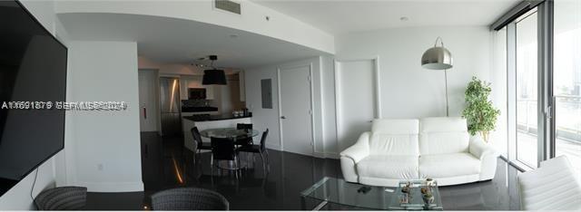 A modern living room with a white sofa, glass coffee table, and an open kitchen area — 92 SW 3rd St # 1802, Miami FL 33130, MIAMI, FL