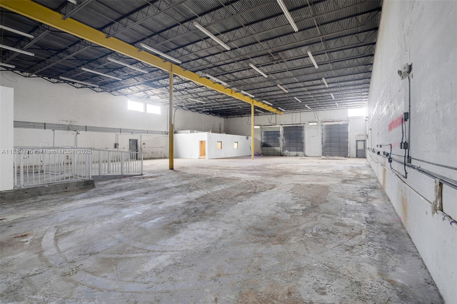 An expansive, empty industrial warehouse space features a high ceiling, concrete floors, and loading doors — 4201 NW 37th Ct # 3725, Hialeah FL 33142, HIALEAH, FL