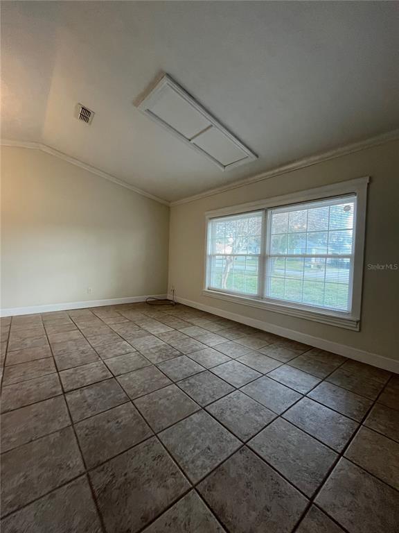 An empty room with tan tile flooring, a vaulted ceiling, and a large window — 3222 HAMMERSMITH ROAD, ORLANDO, FL
