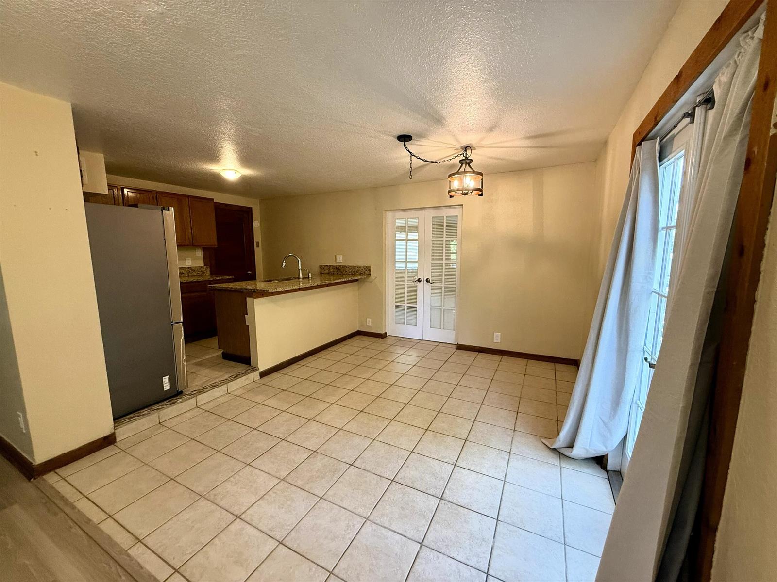 A kitchen with a breakfast bar and tile flooring opens into a dining area — 17503 30th Lane N, Loxahatchee FL 33470, LOXAHATCHEE, FL