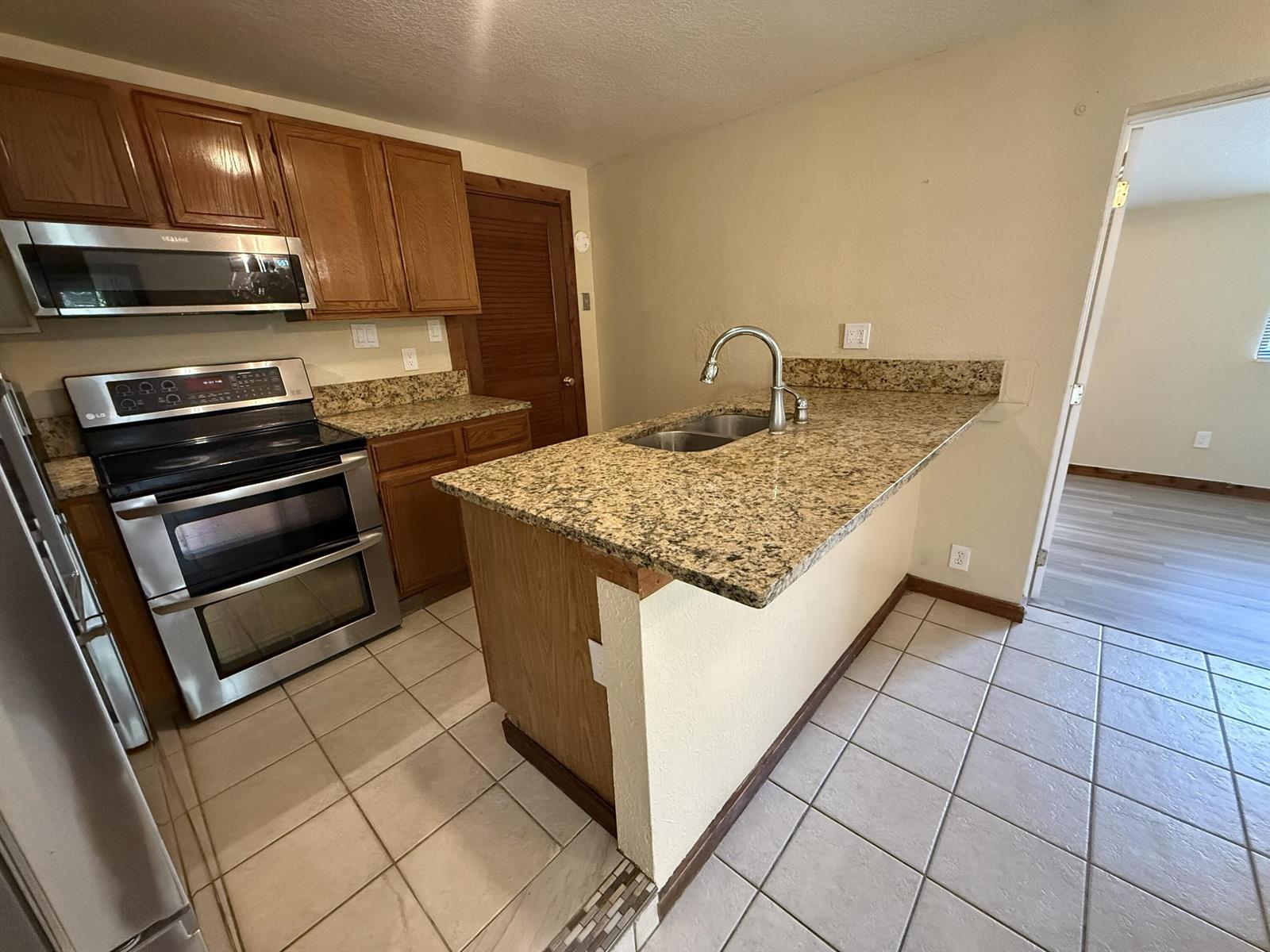 A kitchen features wood cabinets, granite countertops, stainless steel appliances, and a tiled floor — 17503 30th Lane N, Loxahatchee FL 33470, LOXAHATCHEE, FL