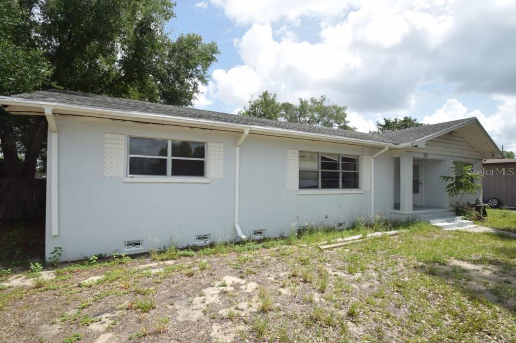 A single-story house with a light-colored exterior, white shutters, and an overgrown front yard — 307 STEEDLY AVENUE, LAKE WALES, FL