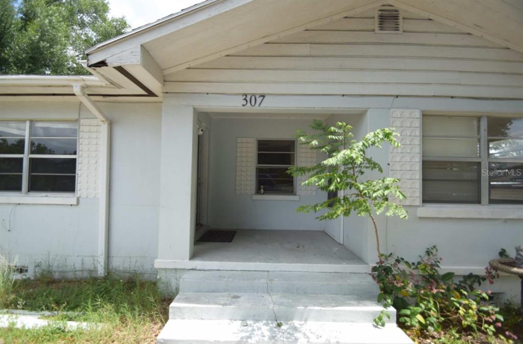 The exterior of a white house features a covered front porch and concrete steps — 307 STEEDLY AVENUE, LAKE WALES, FL