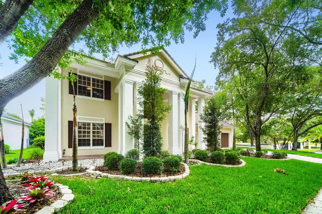 A two-story house with white columns, a tan exterior, and a landscaped front yard — 7601 DEBEAUBIEN DRIVE, ORLANDO, FL