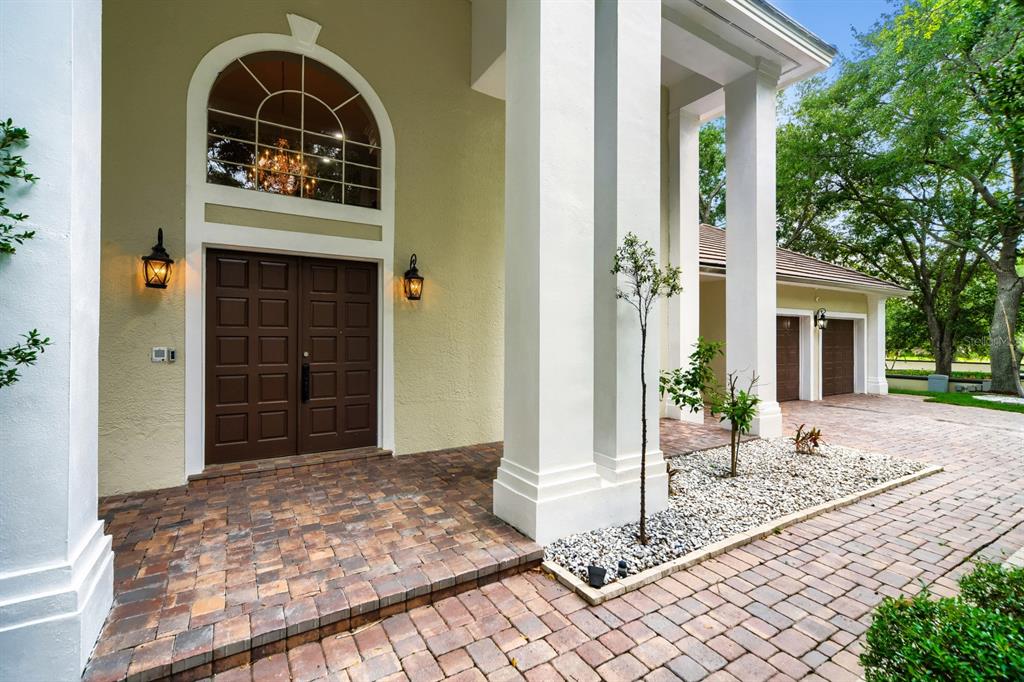 The exterior of a house features a double door entrance, large white columns, and pavers — 7601 DEBEAUBIEN DRIVE, ORLANDO, FL