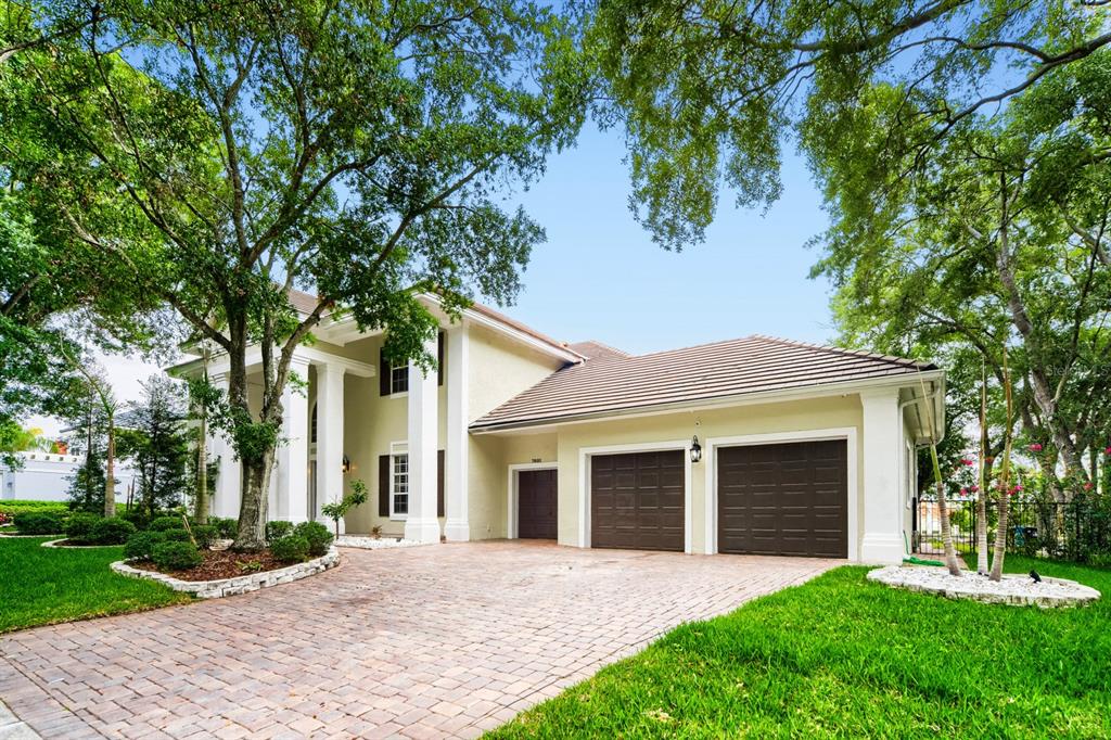 A two-story house with a columned entrance, a brick driveway, and a three-car garage — 7601 DEBEAUBIEN DRIVE, ORLANDO, FL