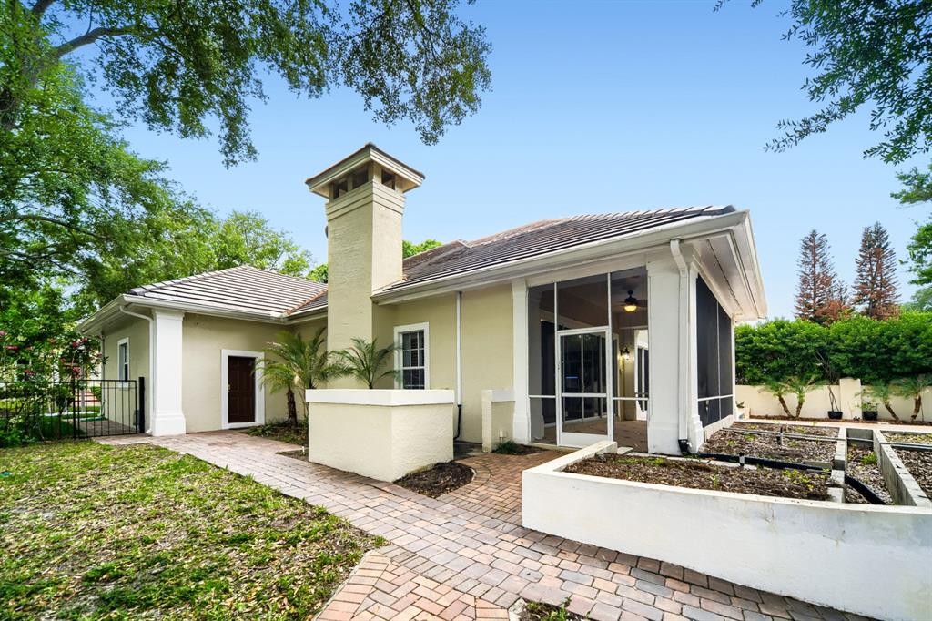 The exterior of a house features a brick walkway, a chimney, and a screened-in porch — 7601 DEBEAUBIEN DRIVE, ORLANDO, FL