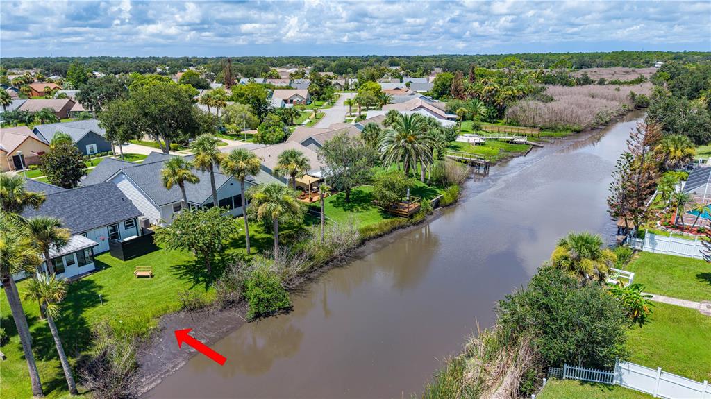 An aerial view shows a residential backyard with a red arrow pointing toward the canal bank — 762 PINE SHORES CIRCLE, NEW SMYRNA BEACH, FL