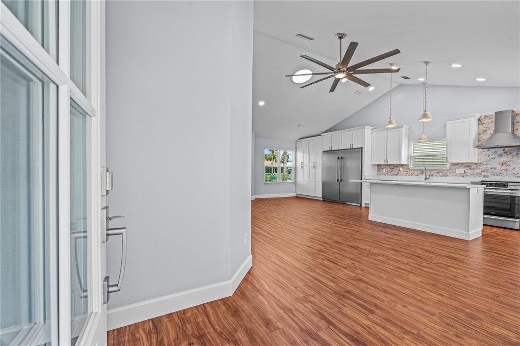 A view from a doorway into a kitchen with white cabinets and wood flooring — 762 PINE SHORES CIRCLE, NEW SMYRNA BEACH, FL