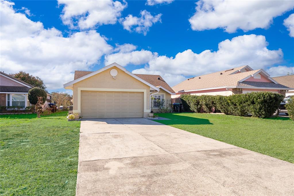 A single-story house with a beige exterior, a two-car garage, and a concrete driveway — 6733 MERITMOOR CIRCLE, ORLANDO, FL
