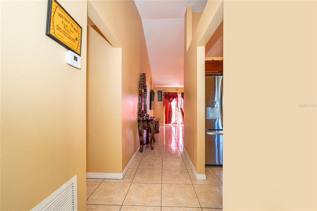 A tiled hallway leads from a foyer toward a kitchen and a living area — 6733 MERITMOOR CIRCLE, ORLANDO, FL