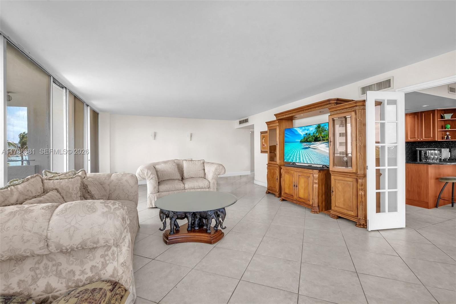A living room features tile floors, a large wooden entertainment center, and a glass-topped coffee table — 11 Island Ave # 512, Miami Beach FL 33139, MIAMI BEACH, FL