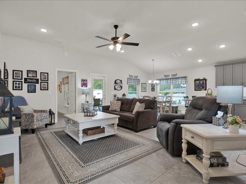 A living room features a dark sofa, a patterned armchair, and a white coffee table — 15648 SE 92ND AVENUE, SUMMERFIELD, FL