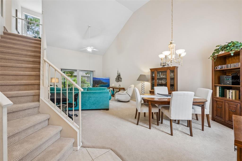 A carpeted dining area and living room with a staircase and vaulted ceilings — 1123 BENT BIRCH COURT, ALTAMONTE SPRINGS, FL
