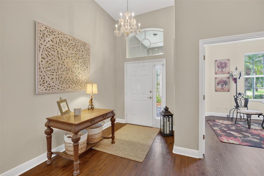 A foyer features a wooden console table, a chandelier, and a large wall-mounted decorative carving — 3650 MEADOWLARK WAY, MELBOURNE, FL