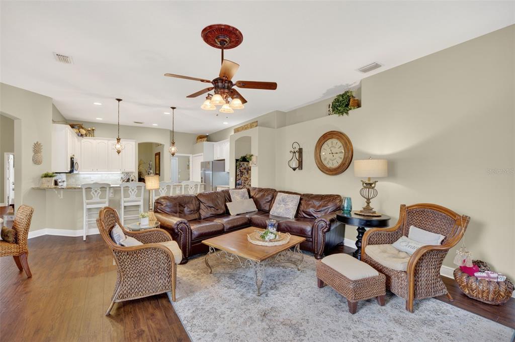 A living room with a brown leather sectional, wicker chairs, and an open kitchen area — 3650 MEADOWLARK WAY, MELBOURNE, FL