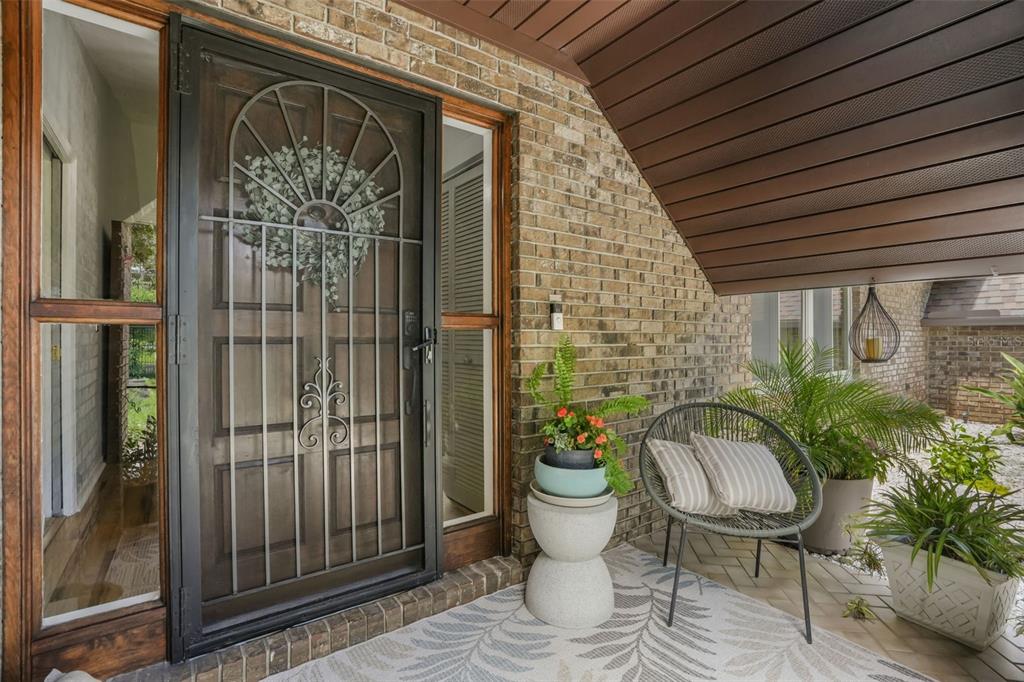 A front porch features a wooden door with a decorative metal security gate and seating — 112 PEACHTREE CIRCLE, DAYTONA BEACH, FL
