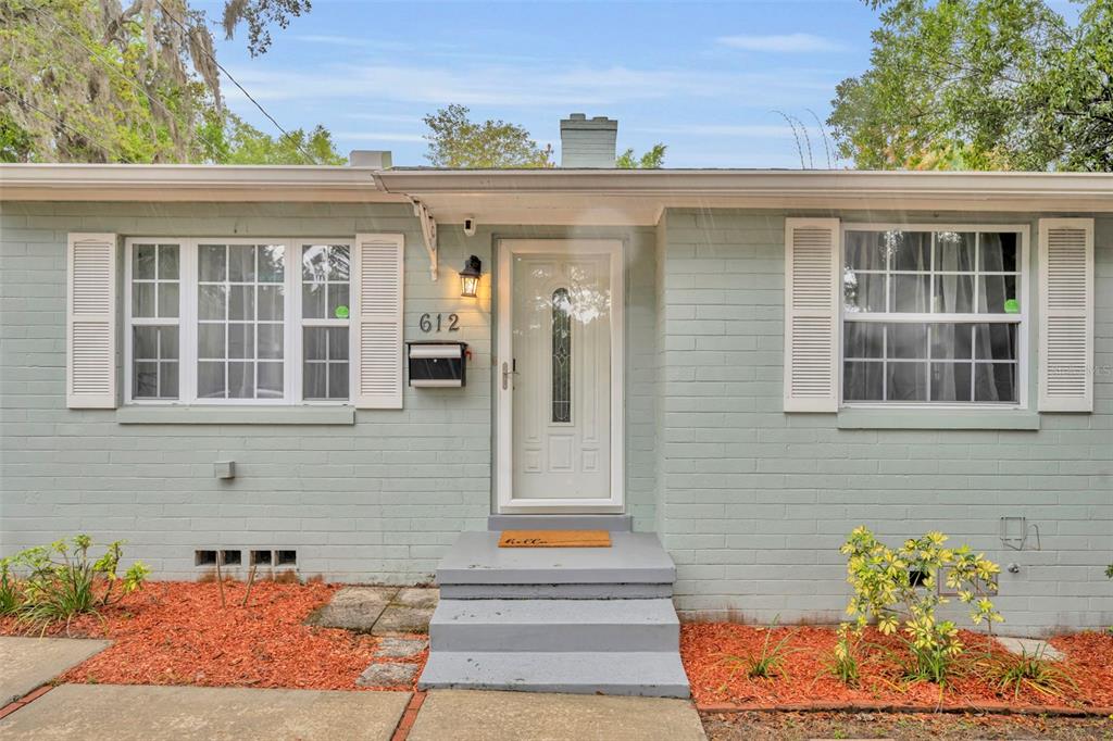 The exterior of a single-story house with light green painted brick and white window shutters — 612 E KALEY STREET, ORLANDO, FL