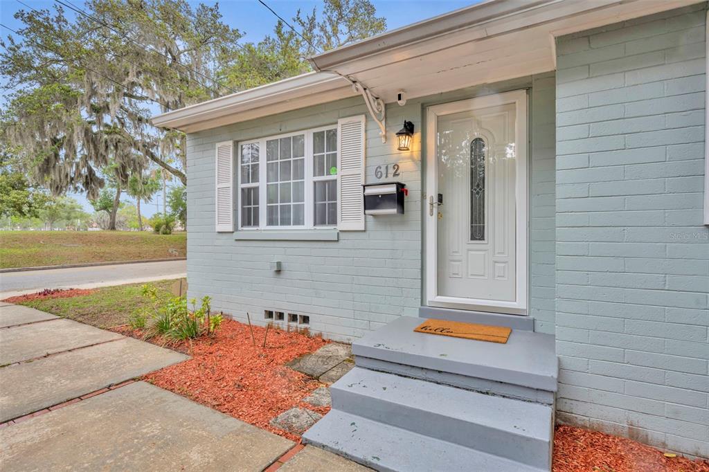 A light blue brick house exterior features a white front door and a small porch — 612 E KALEY STREET, ORLANDO, FL