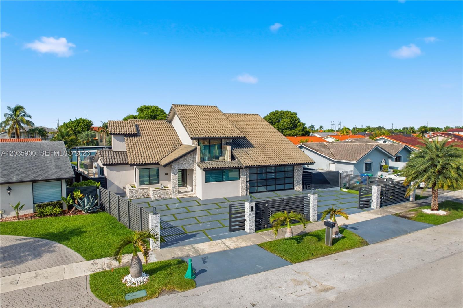A modern two-story house features a tiled roof, stone accents, and a gated driveway — 13330 SW 5th St, Miami FL 33184, MIAMI, FL