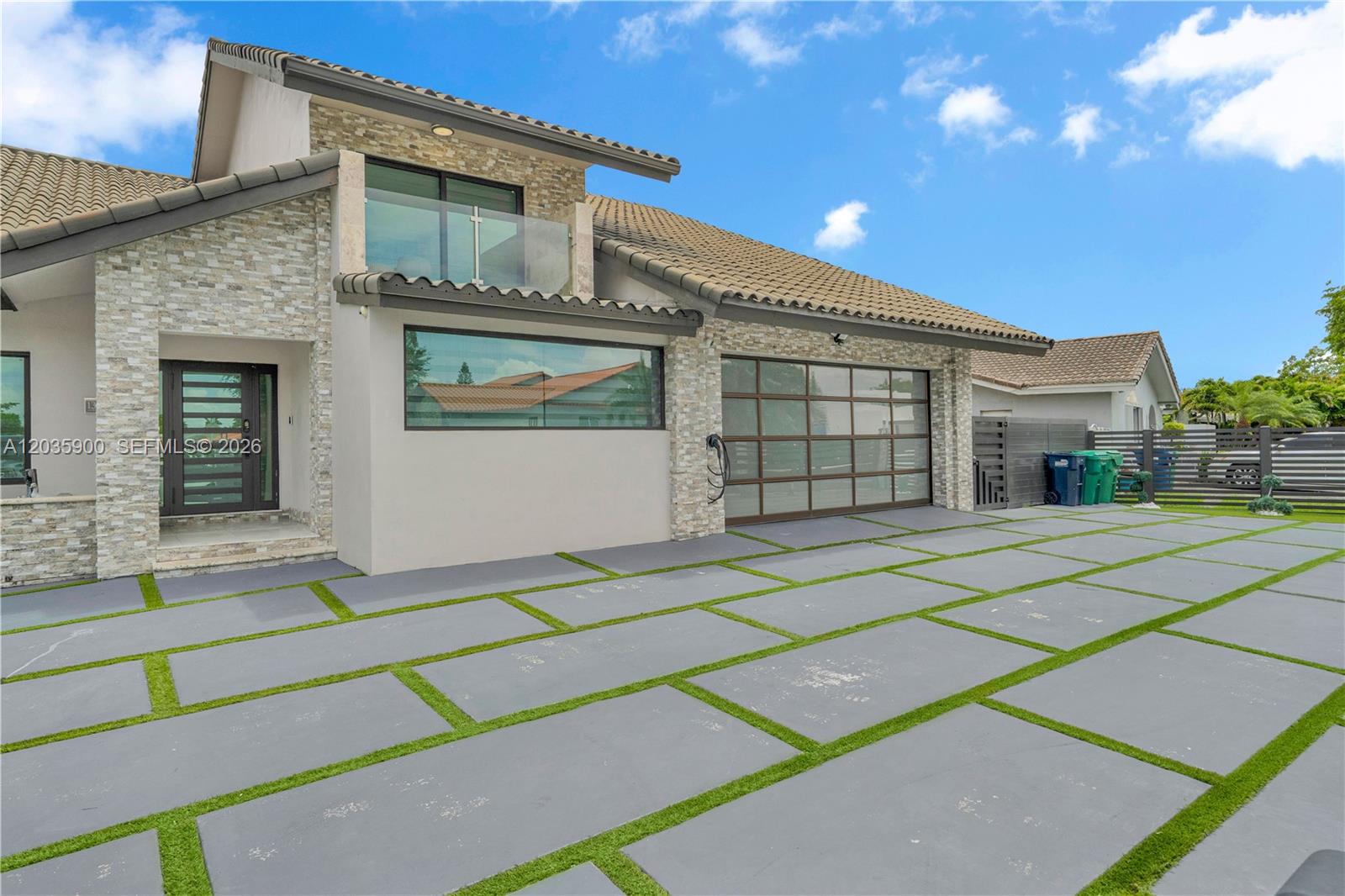 A modern house exterior features a stone facade, a glass garage door, and a paved driveway — 13330 SW 5th St, Miami FL 33184, MIAMI, FL