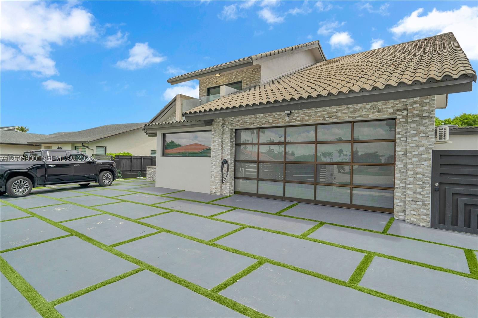A modern house exterior features a glass garage door, stone facade, and a paved driveway — 13330 SW 5th St, Miami FL 33184, MIAMI, FL
