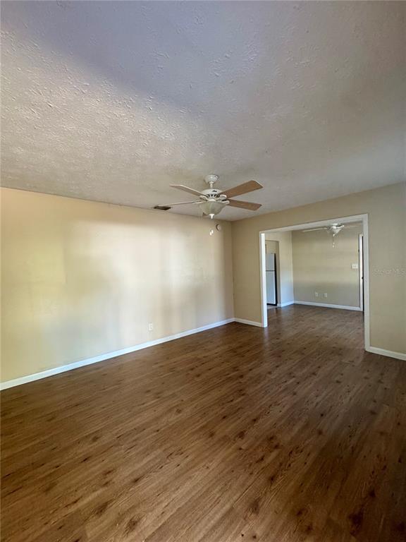A living room with wood-look flooring, a ceiling fan, and an opening to another room — 22368 PANORAMA STREET, BROOKSVILLE, FL