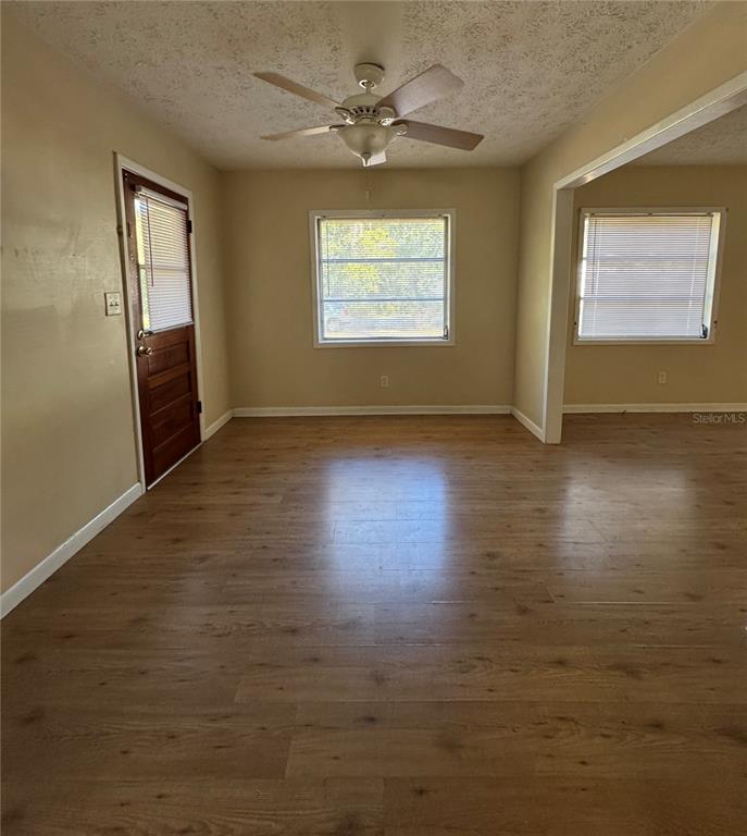 An empty room with light wood-look flooring, beige walls, a ceiling fan, and two windows — 22368 PANORAMA STREET, BROOKSVILLE, FL