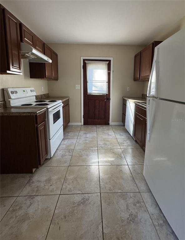 A kitchen features dark wood cabinets, white appliances, and light-colored tile flooring — 22368 PANORAMA STREET, BROOKSVILLE, FL