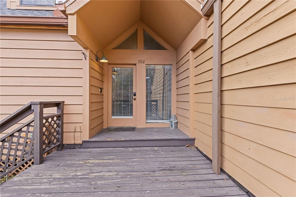 A wooden deck leads to the front entrance of a tan house with siding — 1621 NE 2ND STREET UNIT 302, OCALA, FL