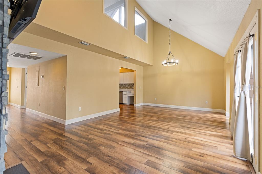A hallway with wood flooring leads to a bathroom and stairs carpeted in light gray — 1621 NE 2ND STREET UNIT 302, OCALA, FL
