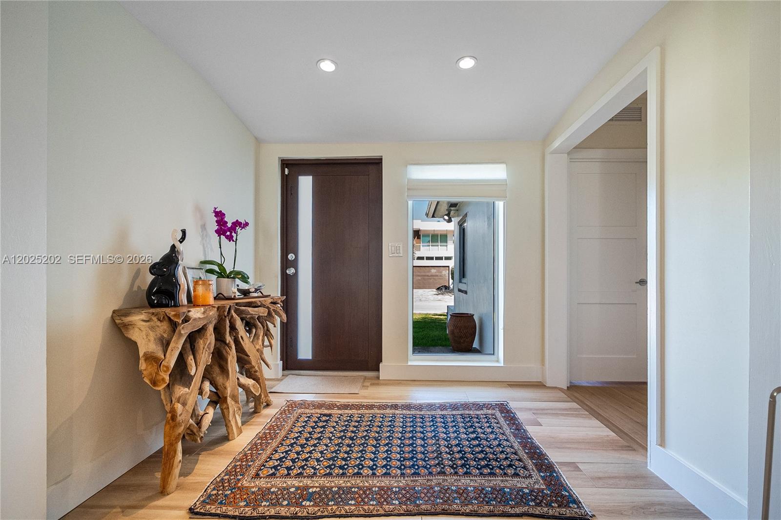 An entryway features a wood root console table, a patterned rug, and a front door — 1260 99th St, Bay Harbor Islands FL 33154, BAY HARBOR ISLANDS, FL