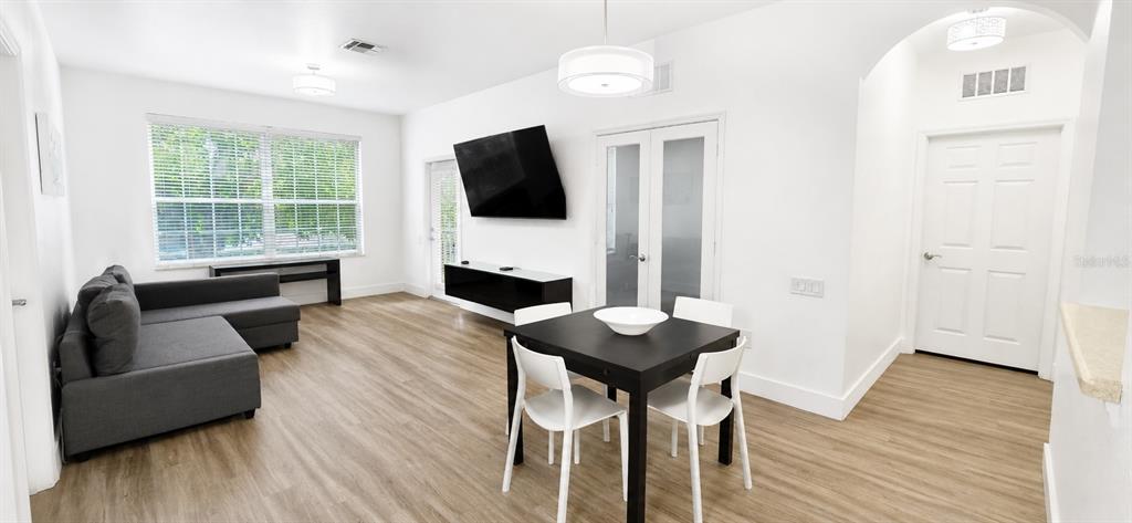 A living and dining area features light wood floors, a gray sectional, and a television — 3326 ROBERT TRENT JONES DRIVE UNIT 209, ORLANDO, FL