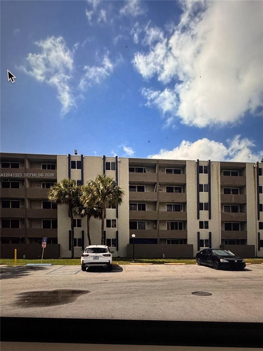 A multi-story apartment building with a parking lot in the foreground under a cloudy sky — 10090 NW 80th Ct # 1241, Hialeah Gardens FL 33016, HIALEAH GARDENS, FL