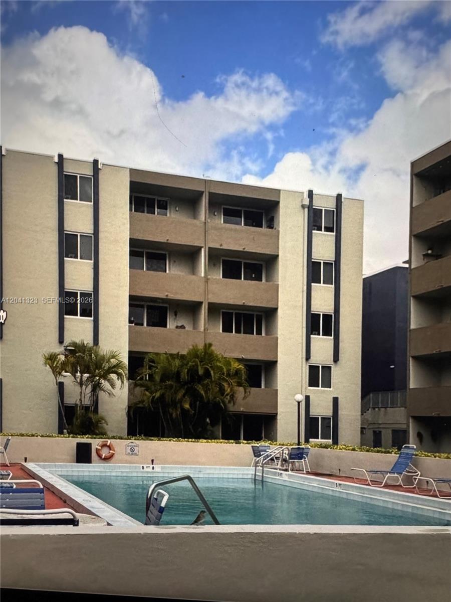 A swimming pool sits in front of a multi-story apartment building with balconies — 10090 NW 80th Ct # 1241, Hialeah Gardens FL 33016, HIALEAH GARDENS, FL