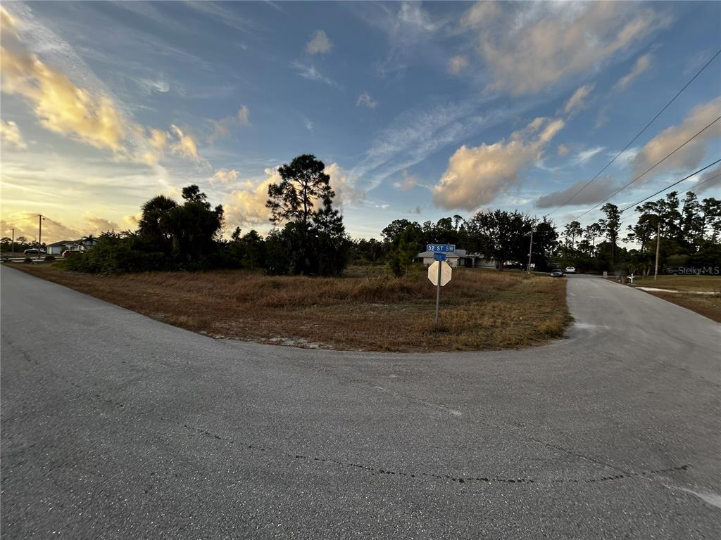 A vacant, grassy corner lot sits at the intersection of two paved residential streets — 3506 32ND STREET SW, LEHIGH ACRES, FL