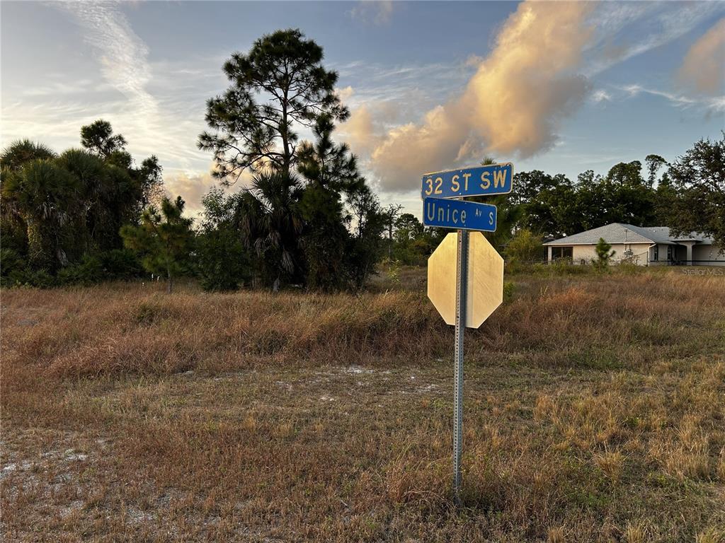 A street sign stands at the corner of a vacant, grassy lot with trees — 3506 32ND STREET SW, LEHIGH ACRES, FL
