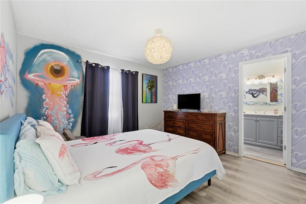 A bedroom features a flamingo-patterned bedspread, a jellyfish mural, and a wave-patterned accent wall — 527 BEACH ROAD, SARASOTA, FL