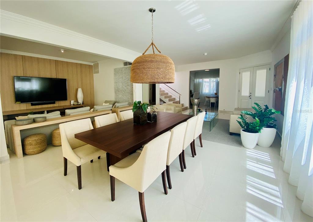 A dining area with a dark wood table and chairs sits before a living room — 13 DORADO BEACH EAST STREET, DORADO, PR