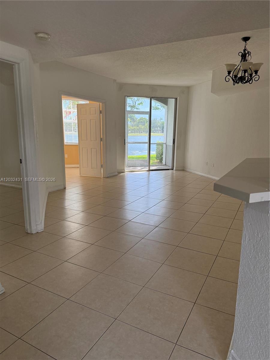 A tiled living area features a sliding glass door with a view of a lake — 715 SW 148th Ave # 611, Sunrise FL 33325, SUNRISE, FL