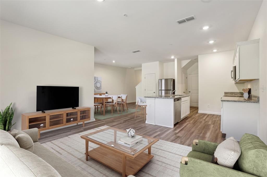 An open-concept living room and kitchen featuring wood-look flooring, a glass coffee table, and cabinetry — 2566 GREY HAWK DRIVE,, KISSIMMEE, FL