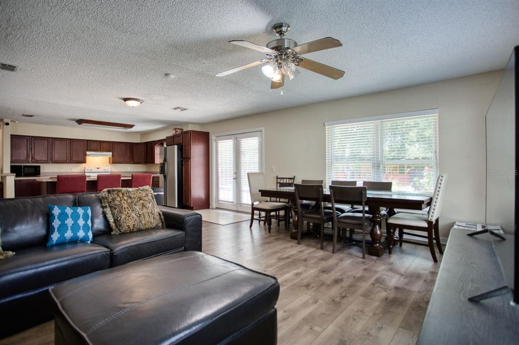 A living room with a leather sofa, dining area, and kitchen with dark wood cabinets — 7408 NAVEL TREE COURT, ORLANDO, FL